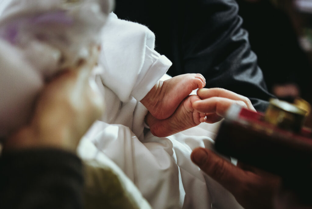 christening of little baby in church, close-up feet and priest hand