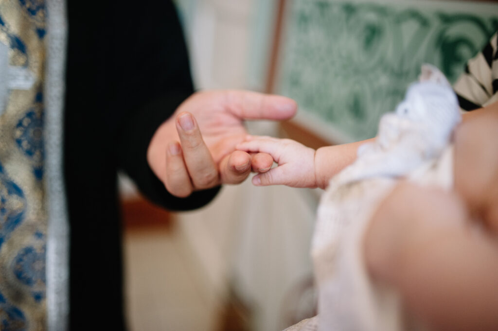 holding baby hand during christening Orthodox baptism