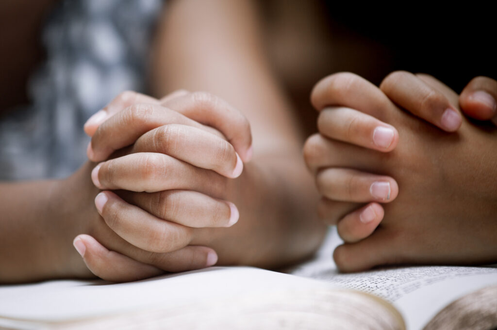 Two Little girl hands folded in prayer on a Holy Bible together  for faith concept in vintage color tone